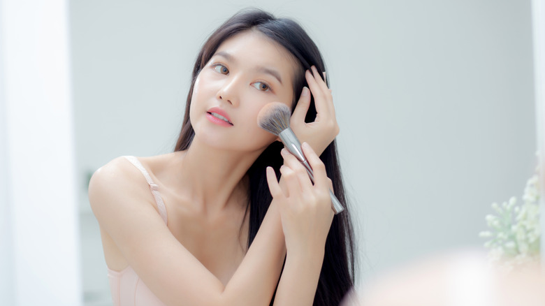 Asian woman applying powder