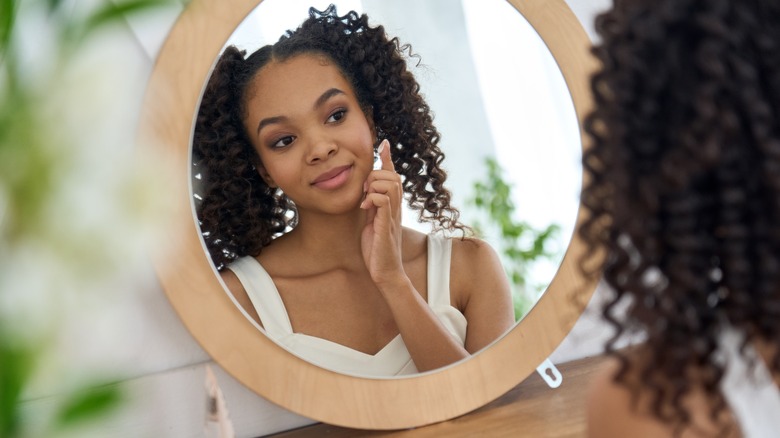 Woman applying moisturizer to face