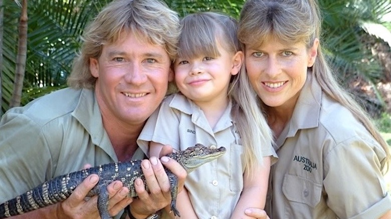 Young Bindi Irwin posing with her parents and a baby crocodile