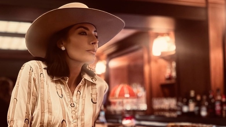 Nicole Sheridan sitting at a bar wearing a Western-style shirt and a cowboy hat.