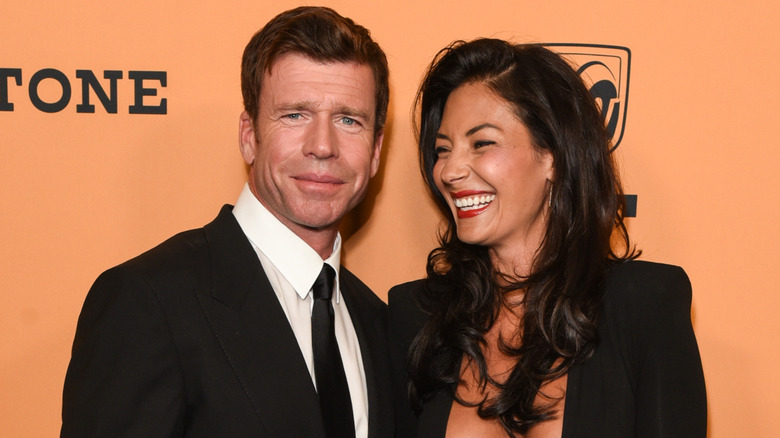 Taylor Sheridan attends a Yellowstone red carpet event as wife Nicole Sheridan laughs while posing next to him.
