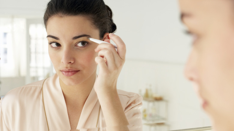 woman tweezing her eyebrows