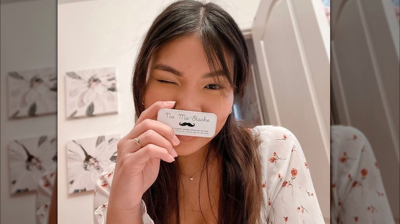 Woman holding a No Mo-Stache tin