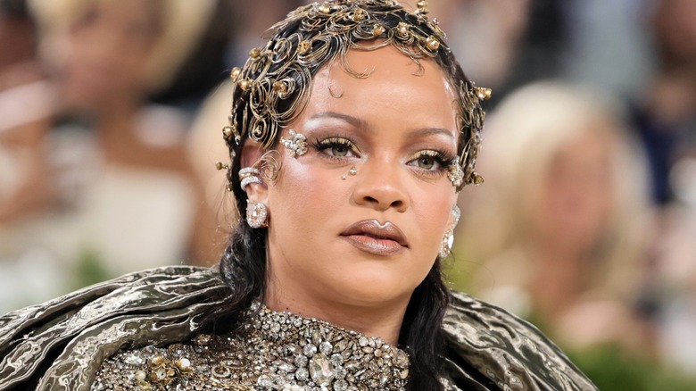 Rihanna posing at the 2026 Met Gala wearing an ornate gold outfit and hair styled with gold accents.