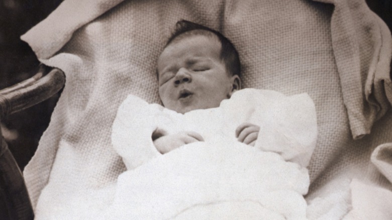 A baby's legs showing her feet wearing vintage knitted pink booties