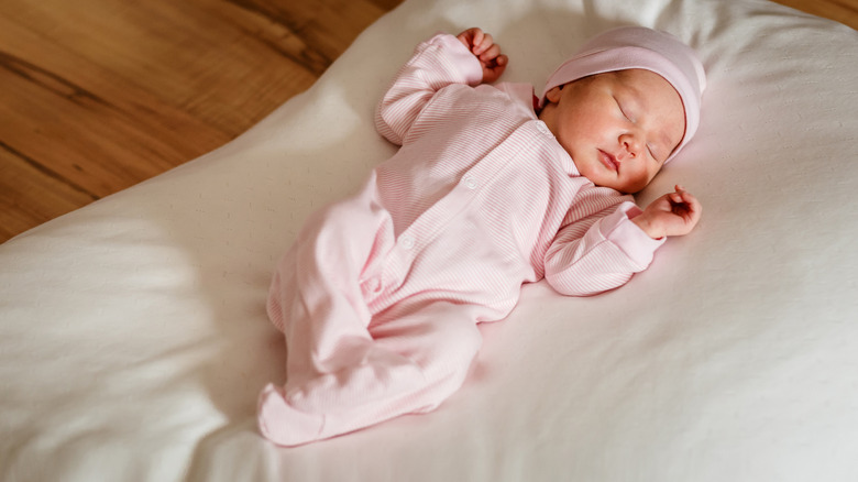 A newborn baby in a pink romper and beanie