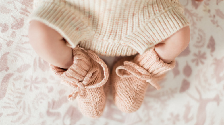 A baby's legs showing her feet wearing vintage knitted pink booties