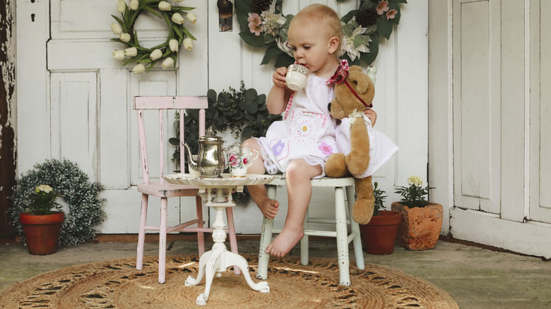 A toddler having a tea party with her teddy bear