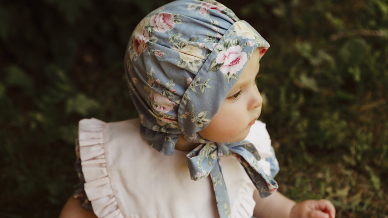 A baby girl wearing a bonnet and bib