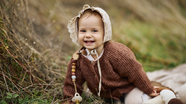 A baby girl in a vintage bonnet and knit outfit