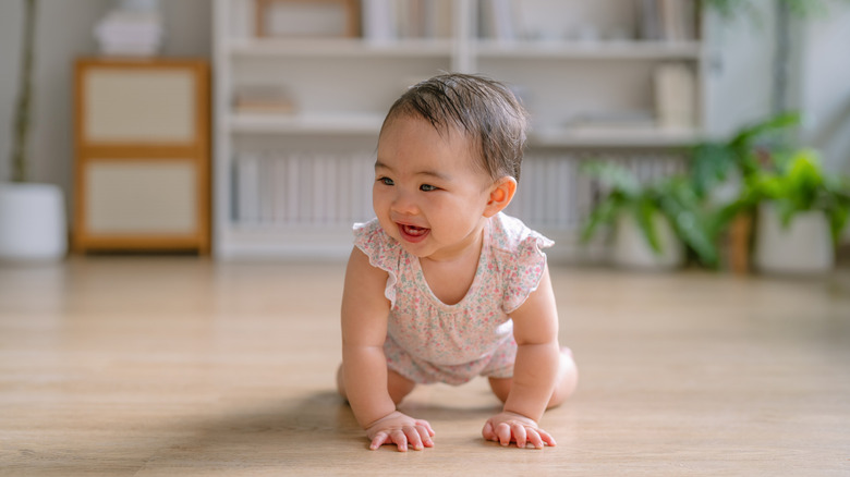 A baby girl in a romper crawling