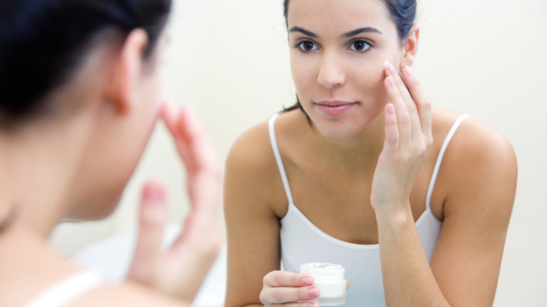 Woman applying cream to her face