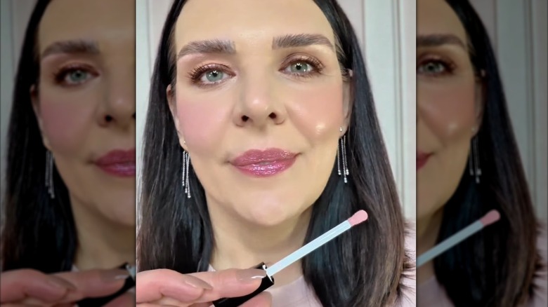 Woman applying pink lip gloss