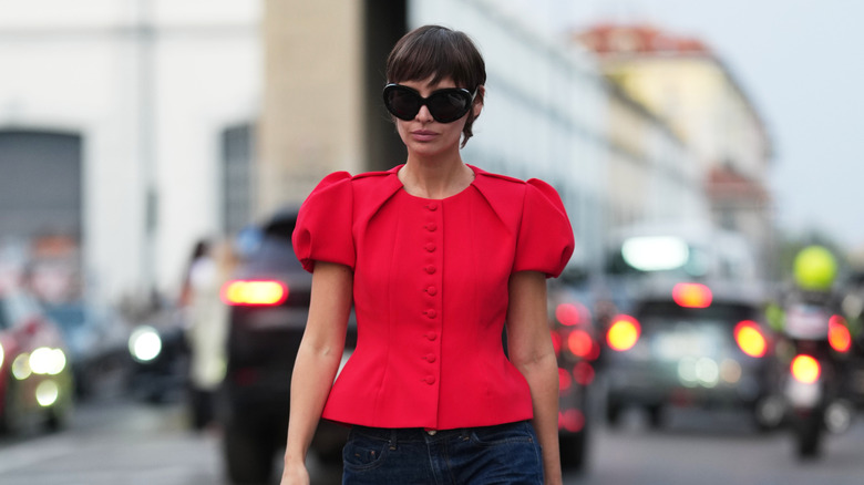 A woman wearing a red blouse with puff sleeves