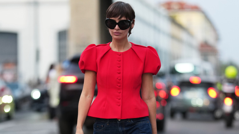 A woman wearing a red blouse with puff sleeves