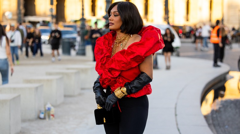 A woman wearing black opera gloves and gold jewelry.