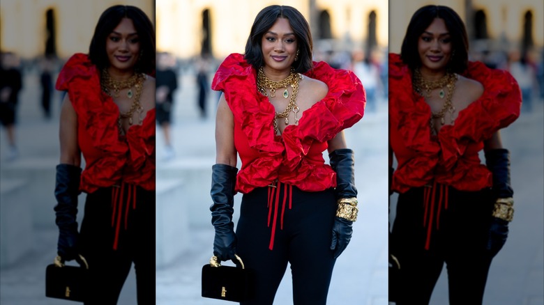 A woman wearing black opera gloves and gold jewelry.