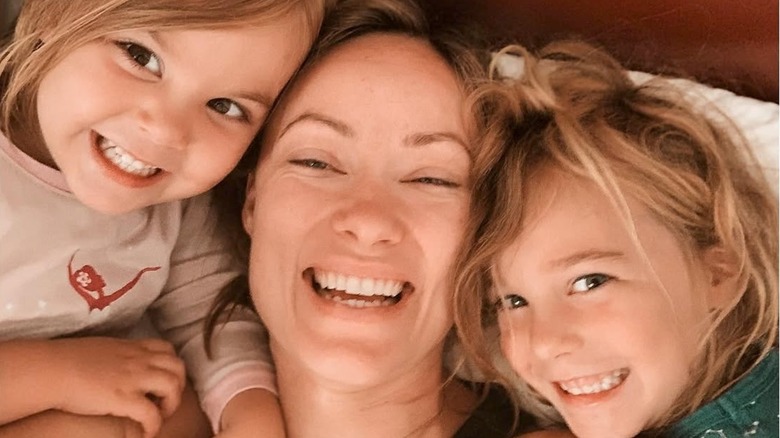 Olivia Wilde with her two children smiling in bed in 2019.