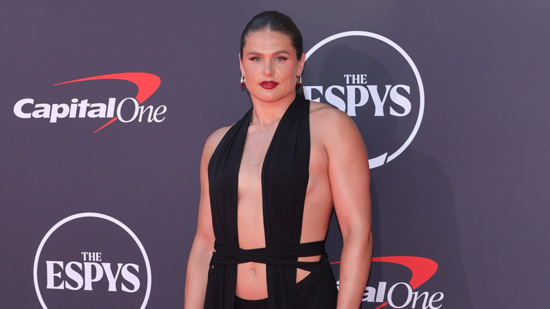 Ilona Maher posing on the red carpet in a black cut-out dress with her hair in a ponytail at The ESPYS.