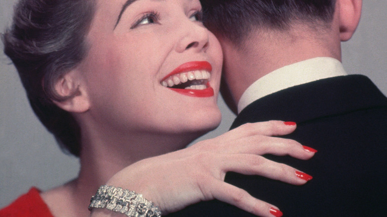 A woman with red nails hugging a man.