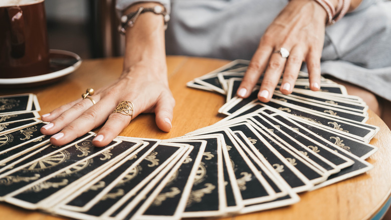 Person spreading tarot deck on table