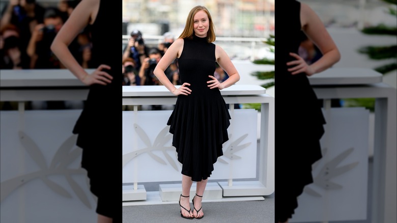 Hannah Einbiner in a black frill dress with open toed sandal shoes.