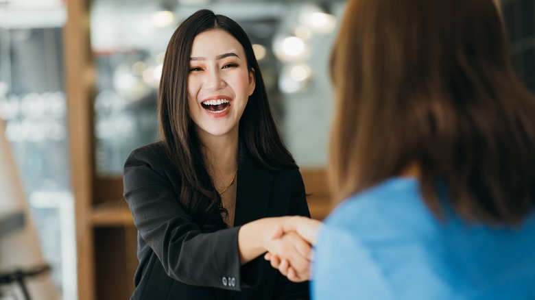 Woman smiling, shaking hands