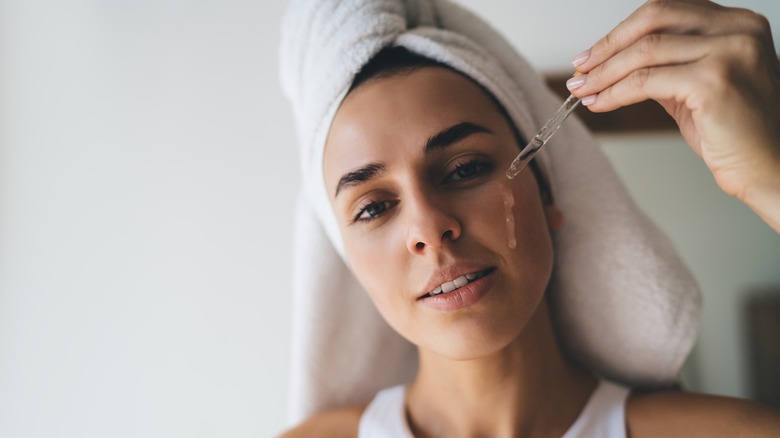 Woman putting serum on face