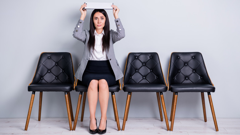 Sitting woman holding notepad overhead