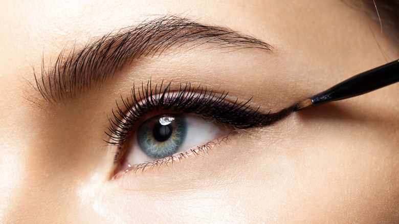Woman applying gel eyeliner with brush