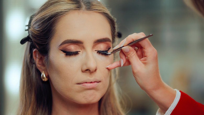 A woman getting thick fake eyelashes applied to her face