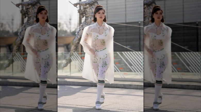 A woman wears a sheer white coat.