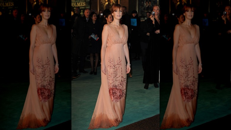 Kelly Reilly walks a red carpet in a peach colored dress with water stains on the bottom of the skirt