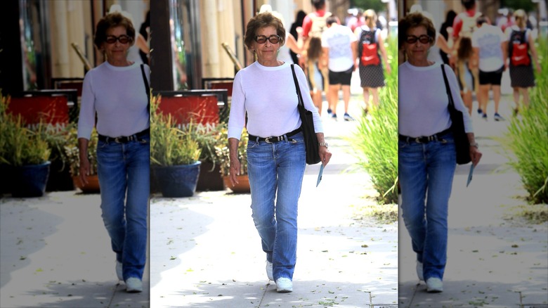 Judy Sheindlin wearing flared jeans and a white long-sleeve with a black belt