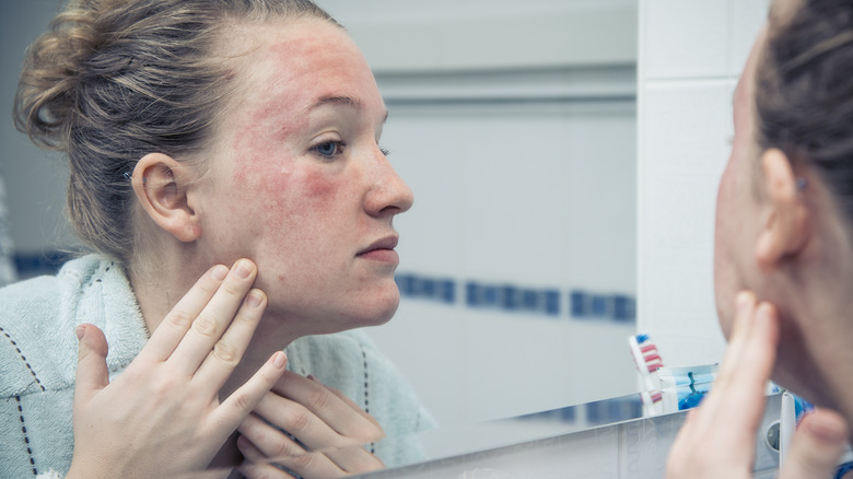 Woman checking skin in mirror