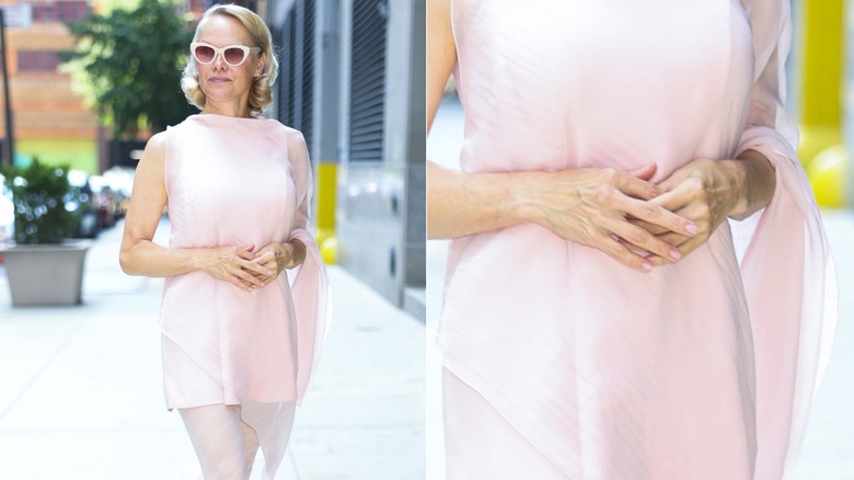 Pamela Anderson wears white sunglasses, a pink dress, and soap nails.