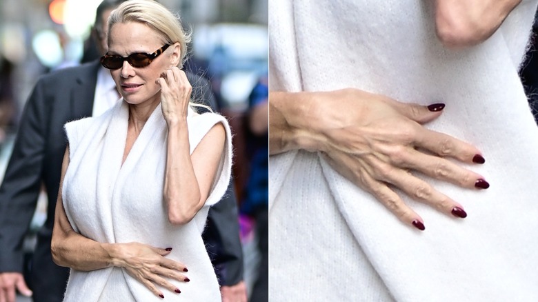 Pamela Anderson wears all white with sunglasses and a red manicure.