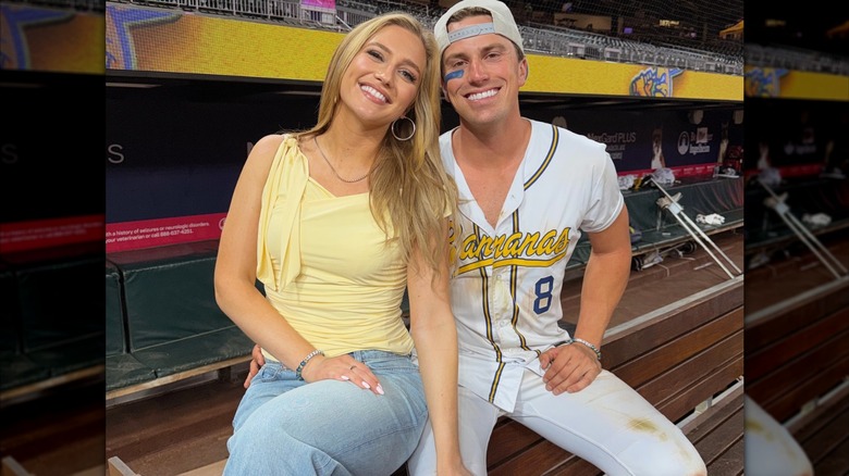 Maggie Sajak wears a yellow top with jeans, posing next to boyfriend and baseball player Jackson Olson at a Savannah Bananas game in May 2026.