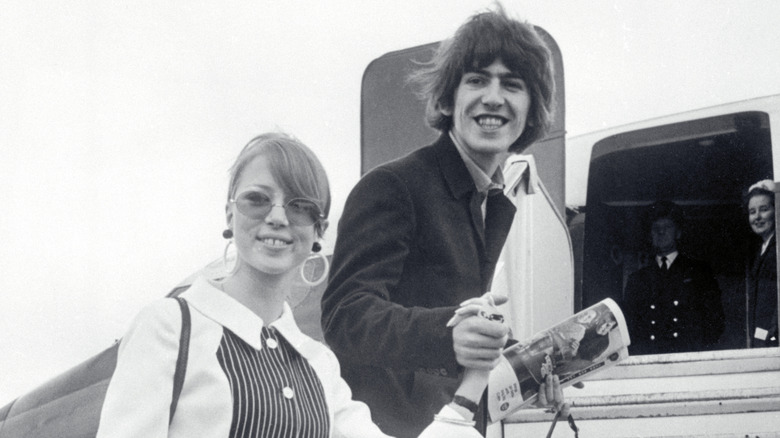Pattie Boyd holding hands with George Harrison boarding a plane