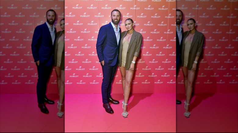 Paulina Grtezky pictured with Dustin Johnson wearing a short dress and blazer