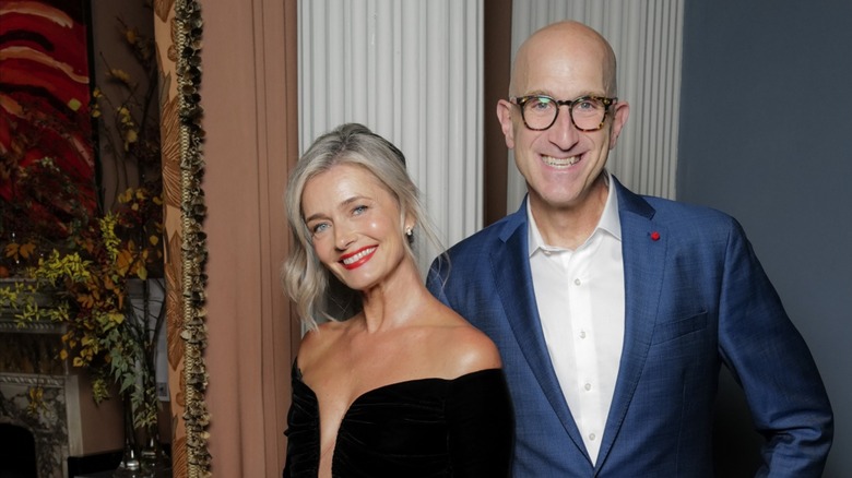Paulina Porizkova wore her gray hair in an updo along with a bold red lip and black eye liner, paired with her strapless plunging black dress, while Jeff Greenstein wore a blue suit with a white button-down shirt underneath while attending the Estee Lauder and Harrods Dinner Celebrating Beauty at Every Age in November 2025 in London, England.