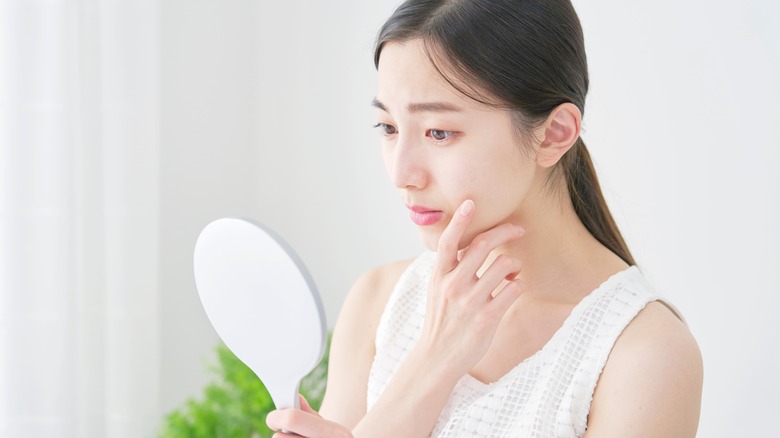 woman checking face on mirror