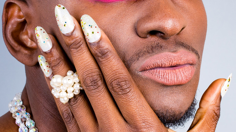 Person with white nails, pearl ring