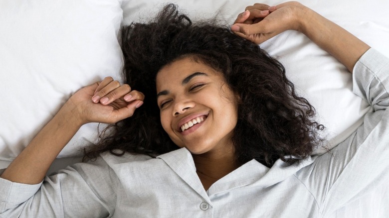 Smiling young woman sleeping in bed