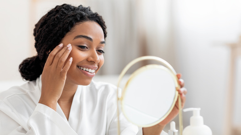 woman looking at face with mirror