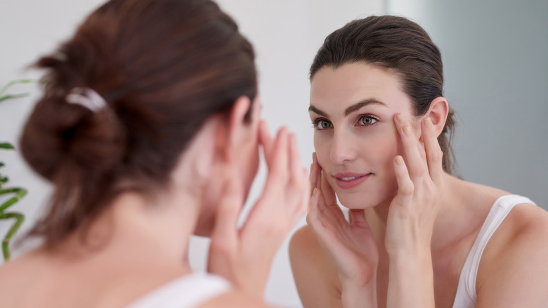 woman touching face in mirror