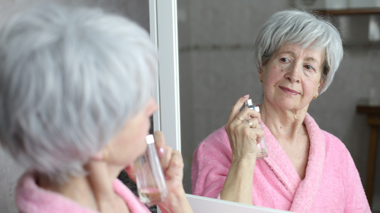 Senior woman using perfume in the bathroom