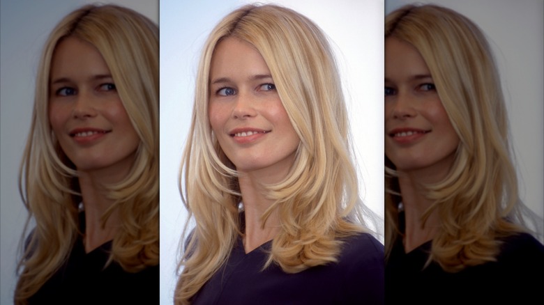 Claudia Schiffer smiling lightly with her head turned to the side, with her blond hair down.