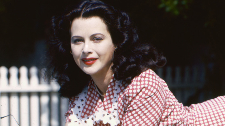 Hedy Lamar lounges on a diving board wearing a gingham dress