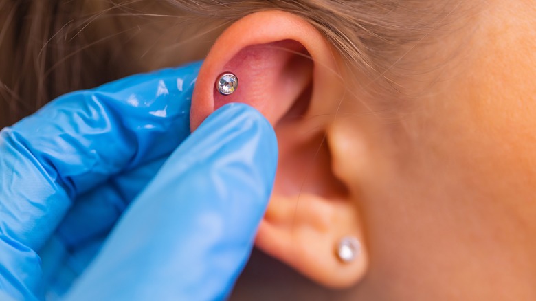 Gloved hand pierced ear